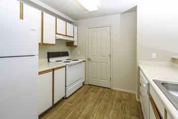 A kitchen with white appliances and wooden floors.
